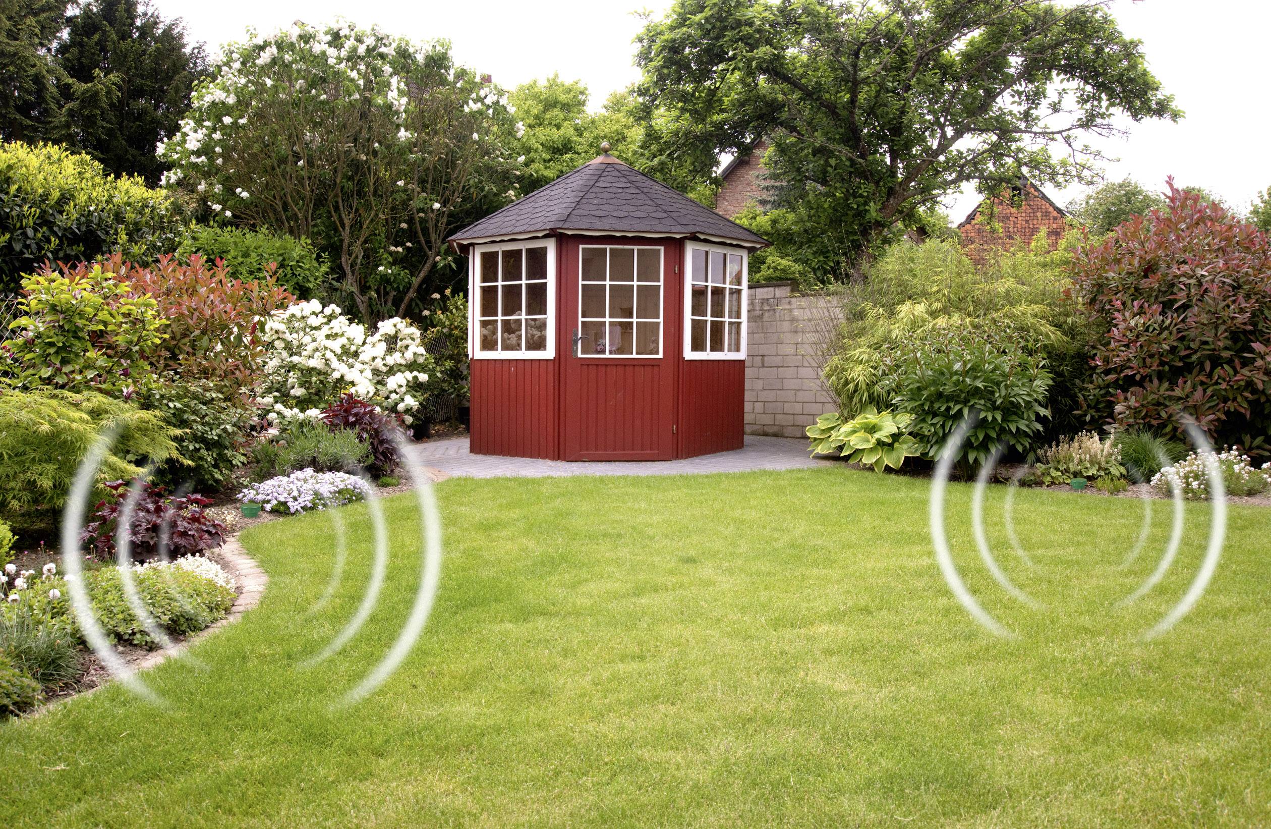 Ein kleiner roter Pavillon steht in einem grünen Garten, umgeben von blühenden Büschen. Grafische Wellenlinien deuten Geräusche an.