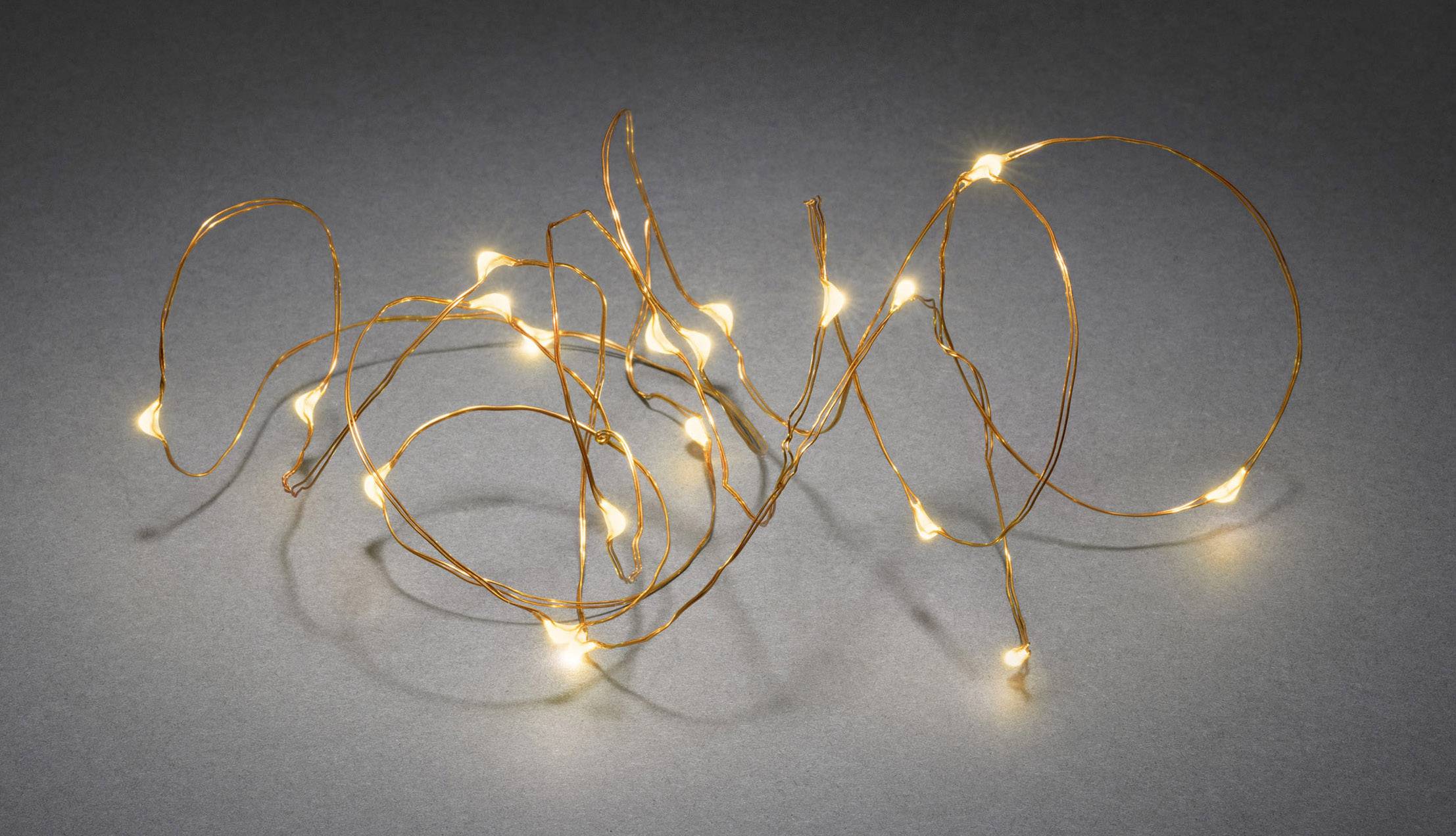 Kupferfarbener Draht mit kleinen leuchtenden LED-Lichtern auf grauem Hintergrund, gebogen in einer zufälligen, geschwungenen Form.
