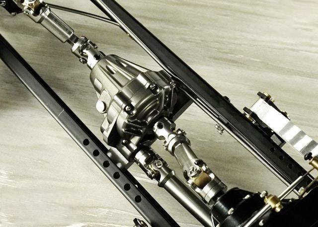 Nahaufnahme eines Metallgetriebes und Antriebsstrangs in einem mechanischen Aufbau, auf einer Holzoberfläche liegend.