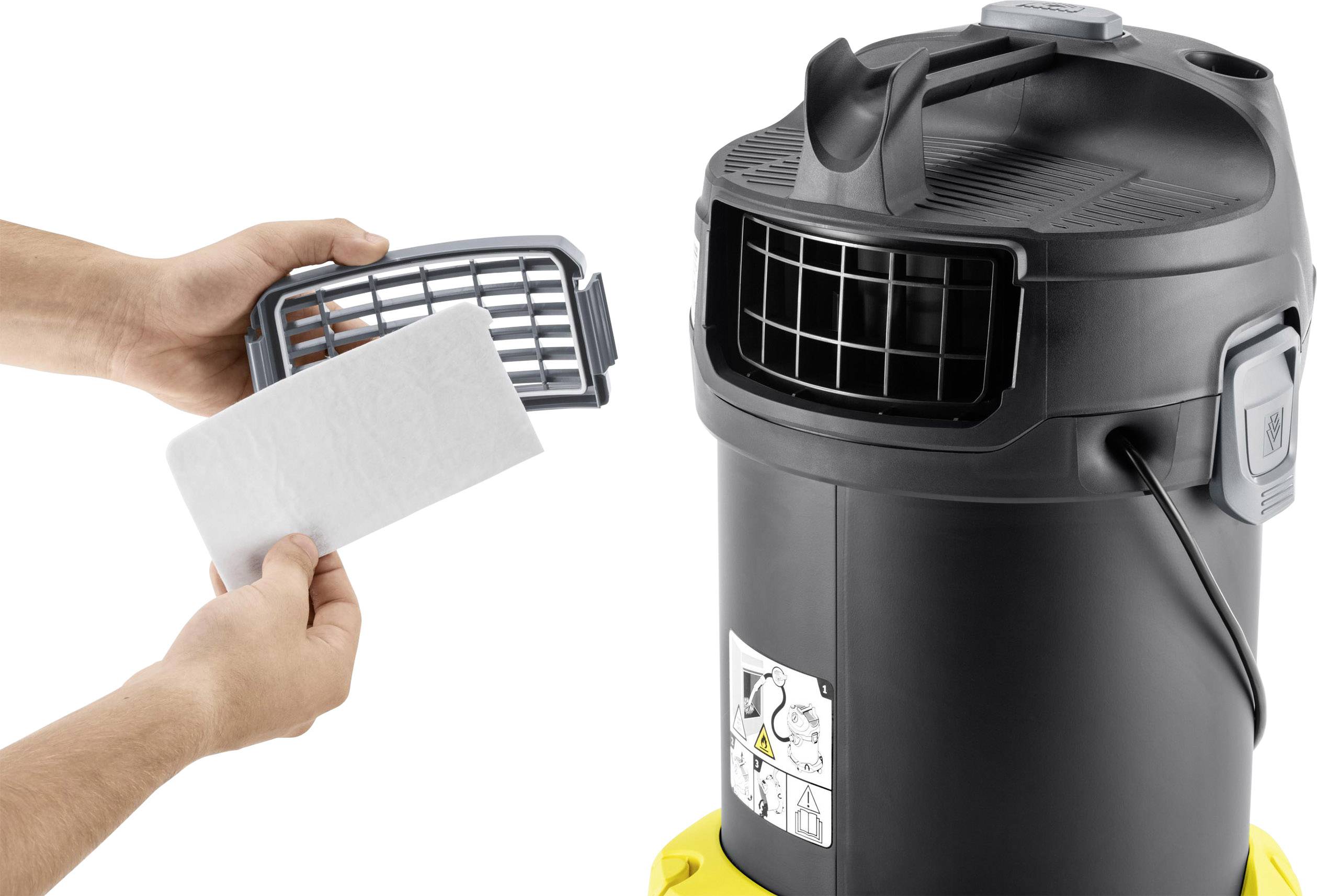 Zwei Hände wechseln einen Filter in einem schwarzen Staubsauger. Der Filter ist rechteckig und wird vor ein Gitter gesetzt.