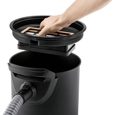 Eine Hand entfernt einen Filter aus einem schwarzen Staubsaugerbehälter. Ein Staubsaugerschlauch ist an der Vorderseite angeschlossen.