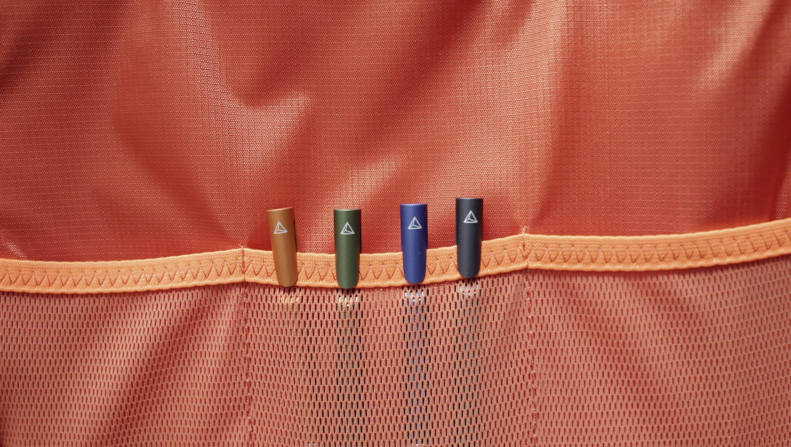 Vier farbige Stifte in einer orangefarbenen Netztasche.