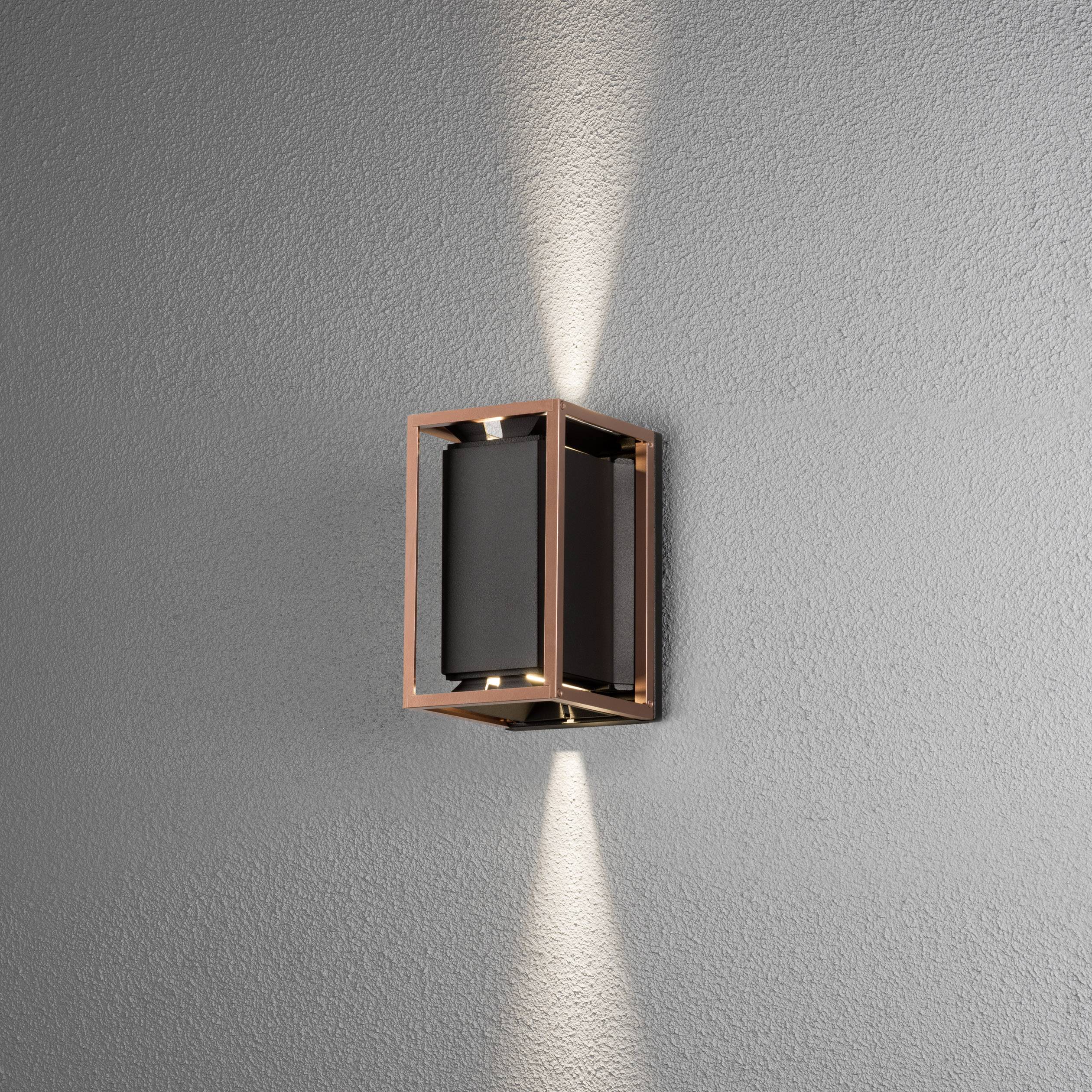 Wandleuchte mit modernem, geometrischem Design. Das Licht strahlt gleichmäßig nach oben und unten auf eine graue Wand.