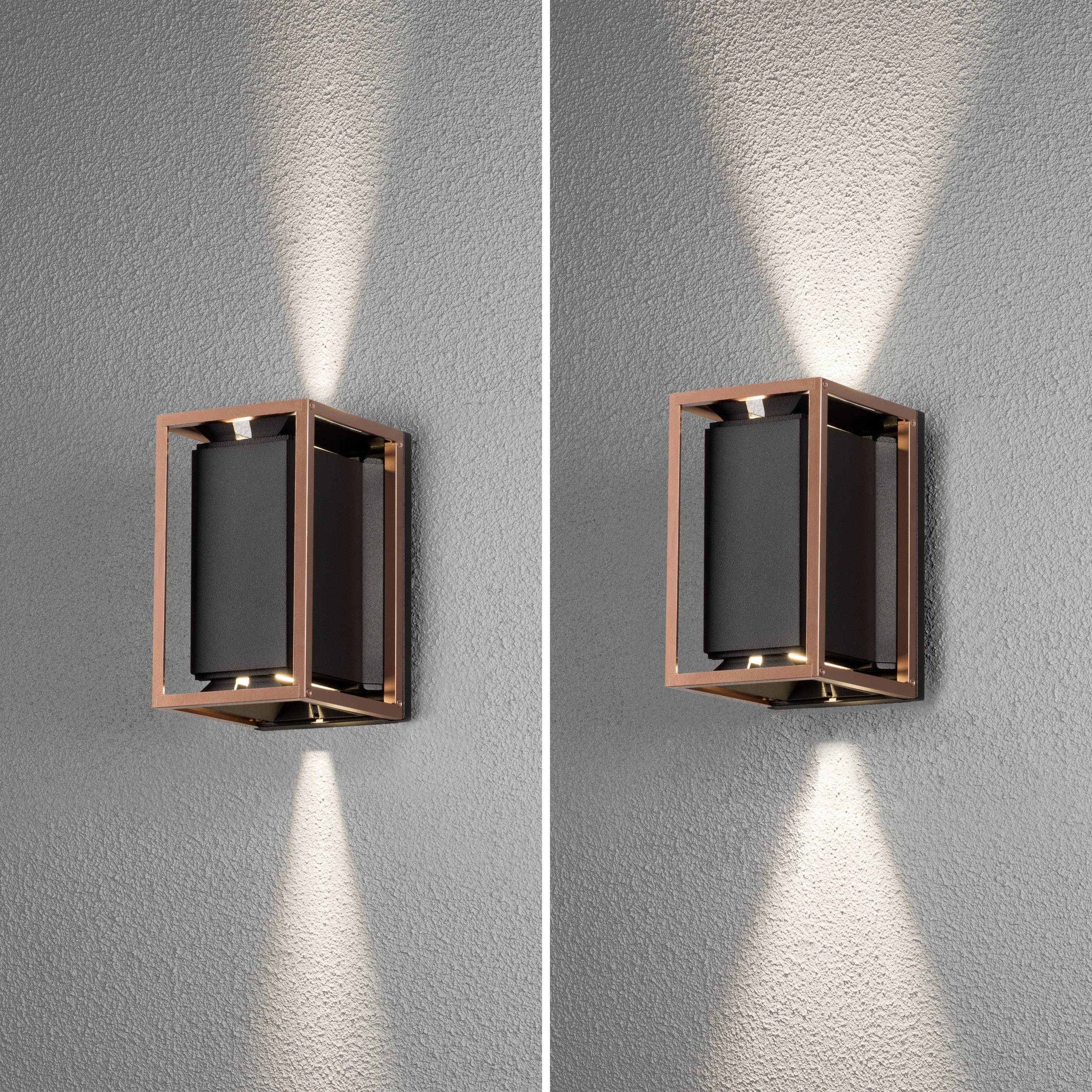 Zwei moderne Wandleuchten mit quadratischem Rahmen aus Kupfer, die nach oben und unten gerichtetes Licht auf eine graue Wand werfen.