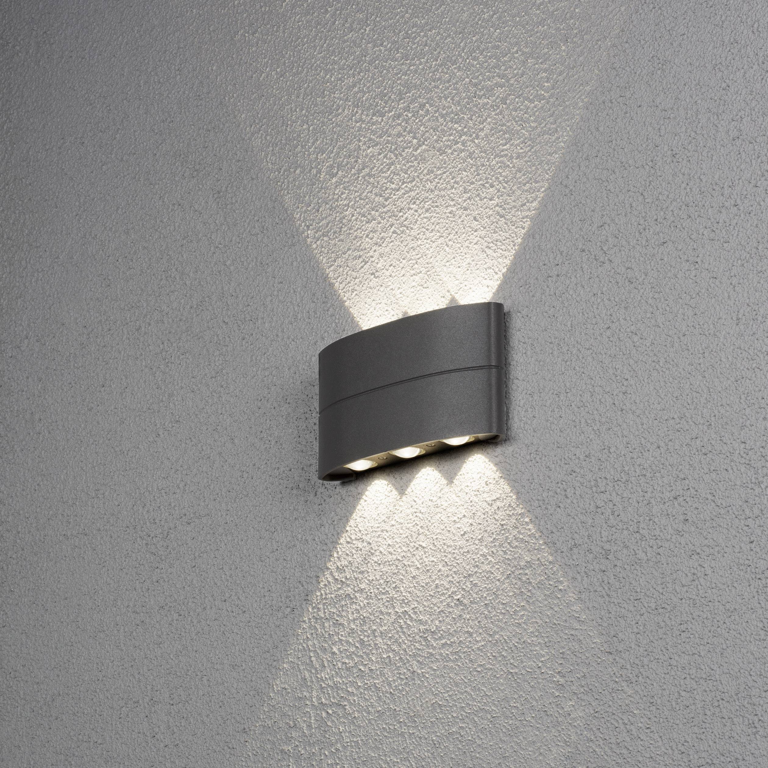 Wandleuchte beleuchtet eine graue Wand mit nach oben und unten gerichteten Lichtstrahlen, erzeugt ein stimmungsvolles Ambiente.