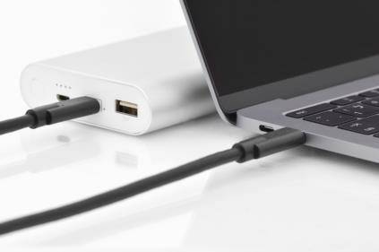 'Ein Laptop ist über ein USB-Kabel mit einer tragbaren Powerbank verbunden.'