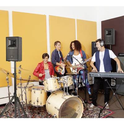 Eine Gruppe junger Musiker probt in einem Studio. Eine Person spielt Schlagzeug, andere spielen Gitarre, Bass und Keyboard. Alle sind fröhlich.