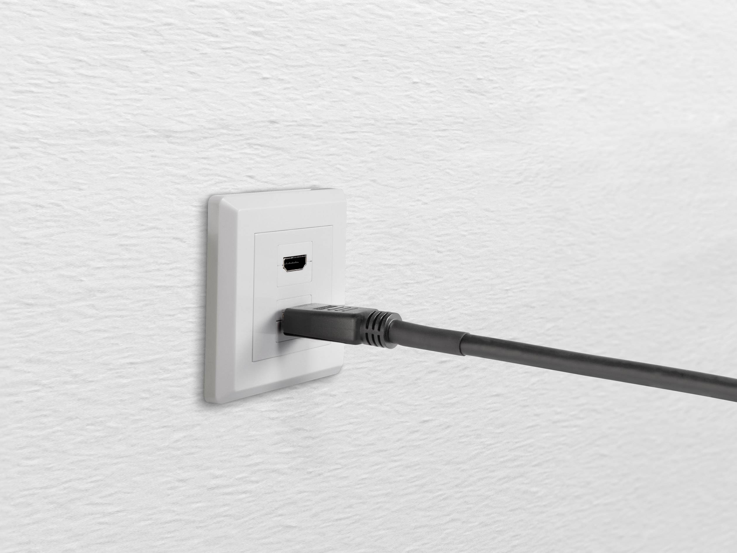 Eine weiße Wandsteckdose mit einer schwarzen HDMI-Kabelverbindung, die in die Buchse eingesteckt ist.