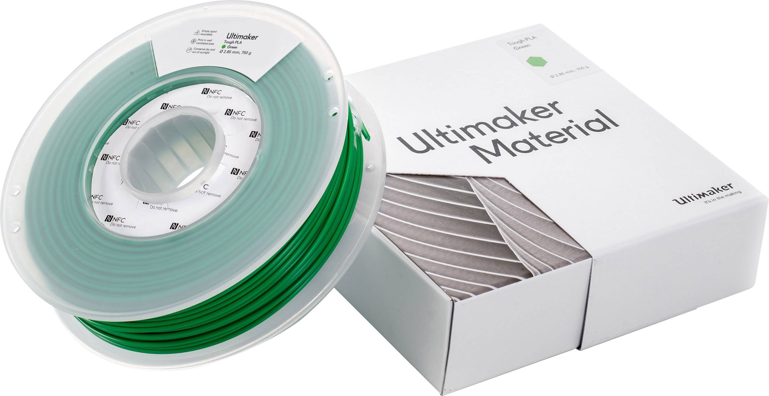 Eine grüne 3D-Drucker-Filamentrolle liegt neben einer weißen Box mit der Aufschrift 'Ultimaker Material'.
