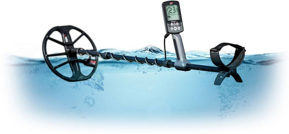 Ein Metalldetektor taucht teilweise unter Wasser auf, während sein Bildschirm über der Oberfläche bleibt und eine Zahl anzeigt.