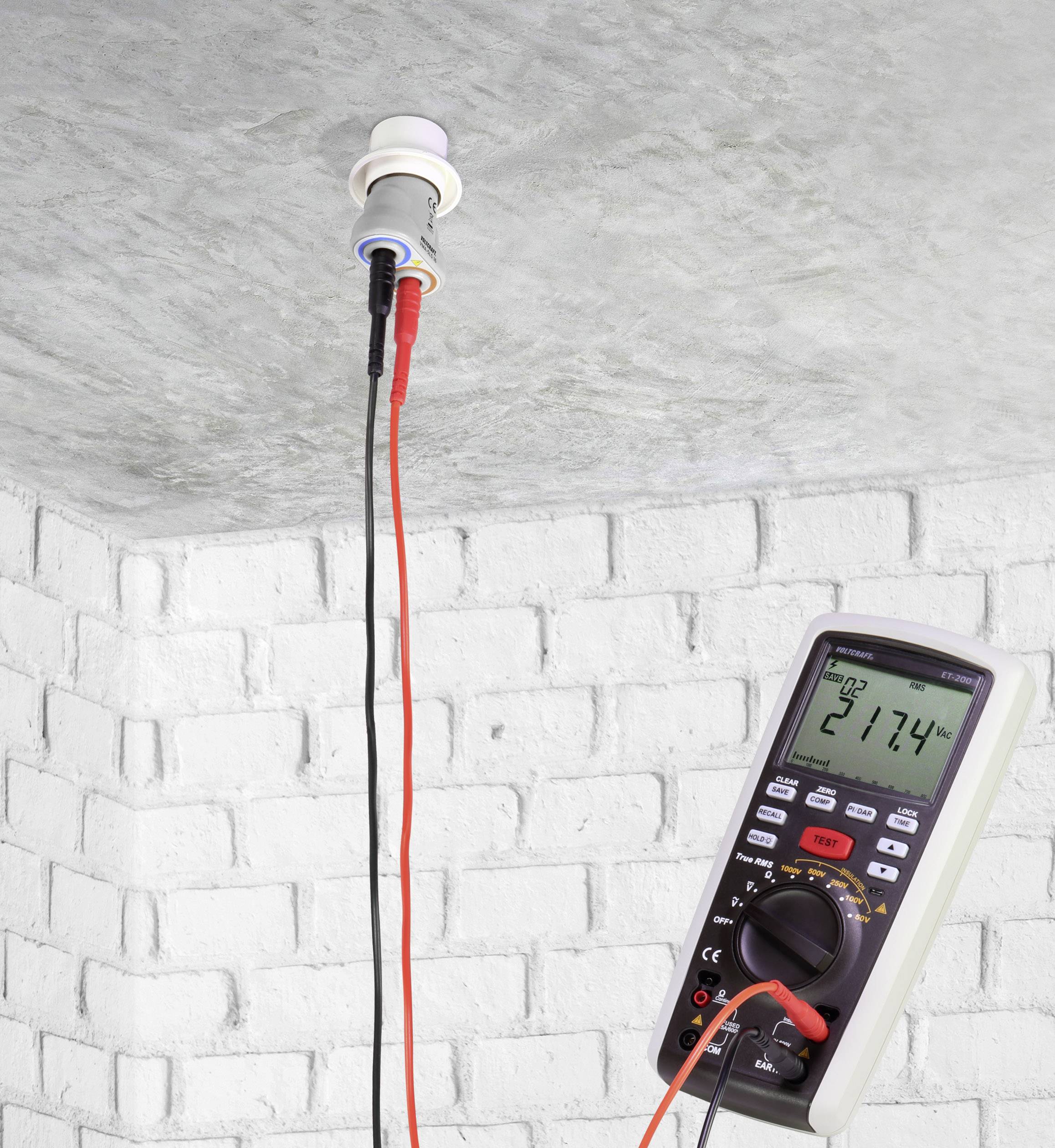Ein Multimeter misst die Spannung an einer Deckenleuchte, zeigt 217,4 Volt im Display. Rote und schwarze Kabel sind angeschlossen.