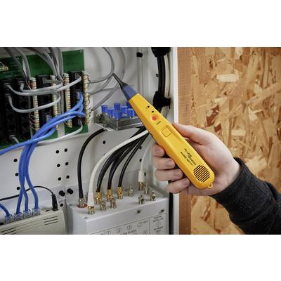 Person hält einen gelben elektrischen Tester neben einem offenen Stromverteilerkasten mit mehreren Kabeln und Anschlüssen.