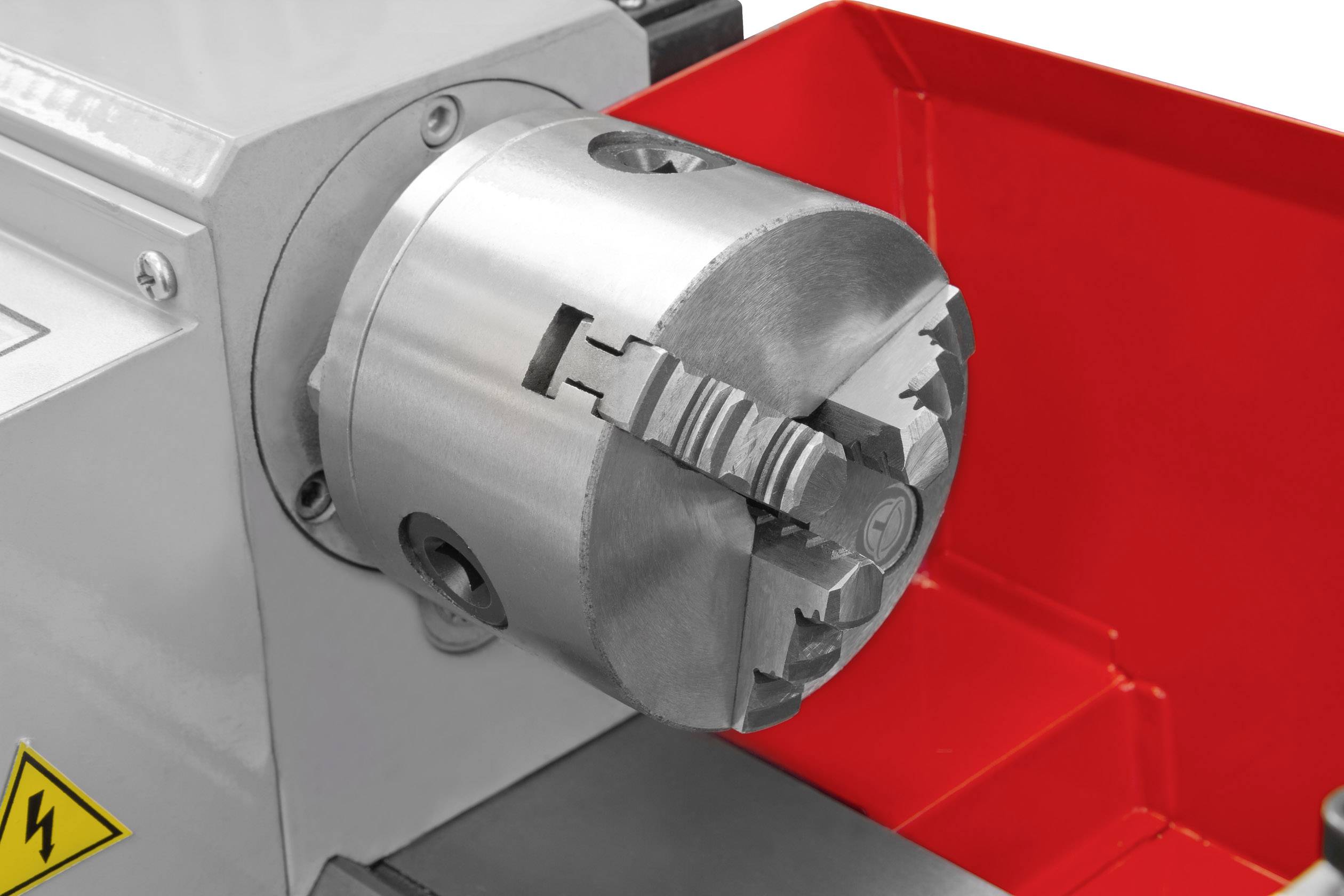 Ein grauer Metallschraubstock mit einem rot umrandeten Gehäuse. Es handelt sich um ein Maschinenteil, vermutlich eine Drehmaschine.