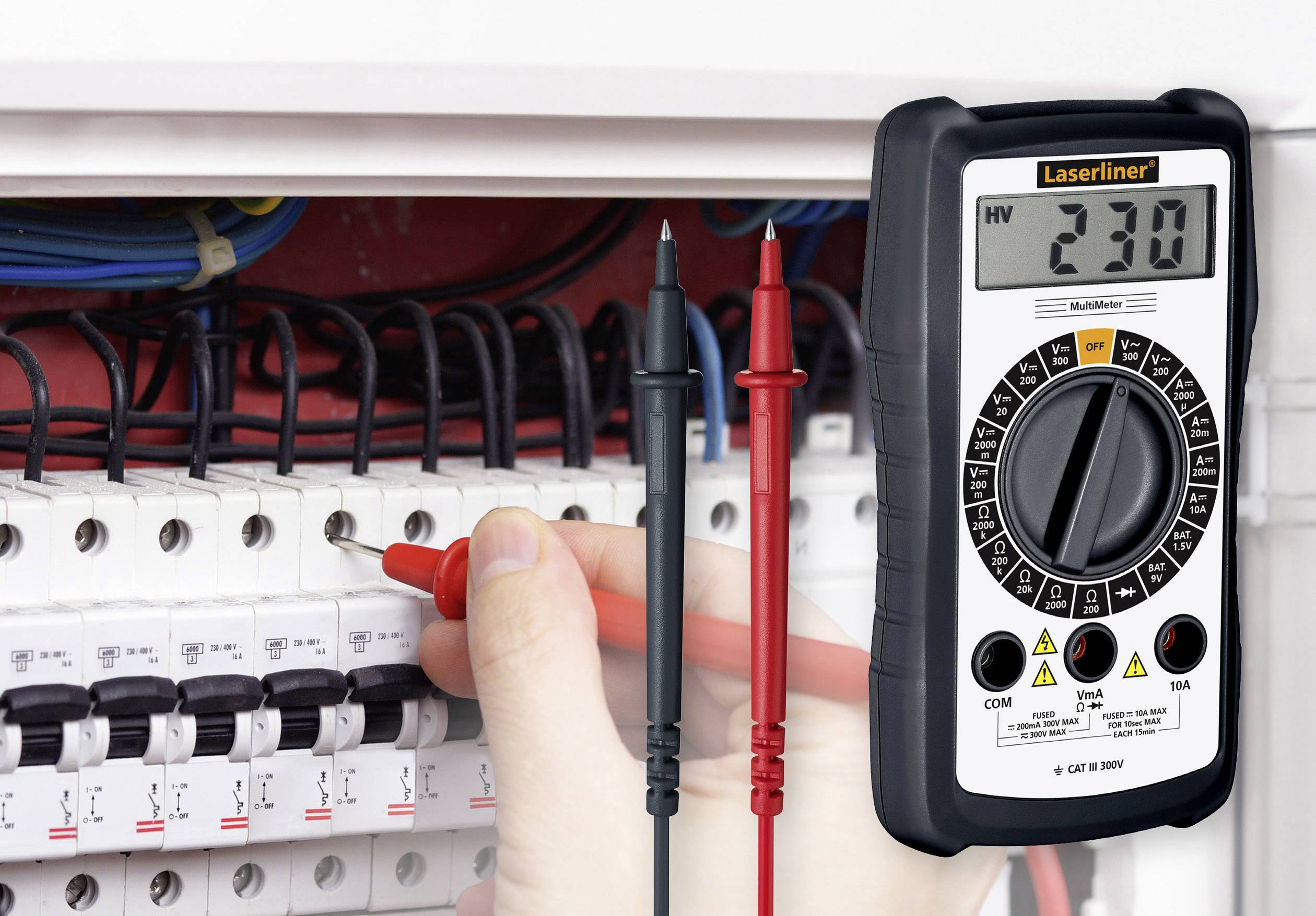 Eine Hand verwendet ein Multimeter, um den Spannungswert (230 V) an einer elektrischen Schalttafel zu messen.