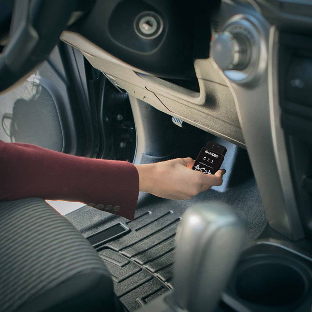 Eine Person im Auto steckt ein USB-Gerät in die Konsole. Der Fahrzeuginnenraum und Armaturenbrett sind sichtbar.