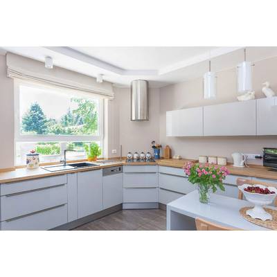 Moderne Küche mit Eckfenster, grauen Schränken, Holzarbeitsflächen. Tisch mit Blumen und Obstschale, sonniger Außenblick.