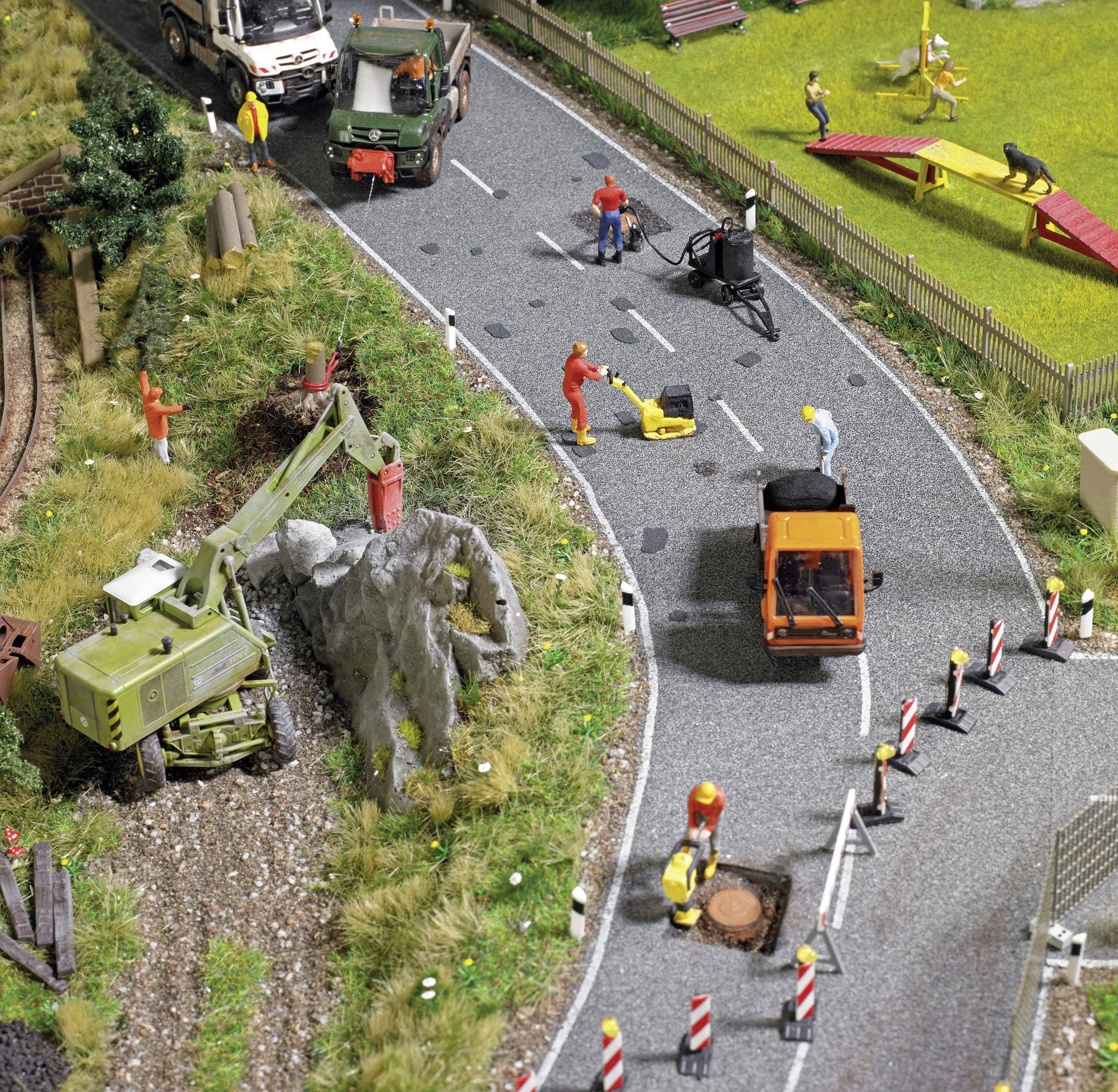 Eine Modelllandschaft zeigt eine Straßenszene mit Baustellenfahrzeugen, einer Baustelle mit Arbeitern und einer nahegelegenen Parkanlage.