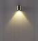 Wandleuchte aus Metall mit warmem Lichtstrahl, der sich nach unten auf eine glatte Wand ausbreitet. Minimalistisches Design.