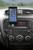 Smartphone in einer Halterung an der Mittelkonsole eines Autos. Auf dem Display sind App-Symbole sichtbar. Radio zeigt 'AUX Connected'.
