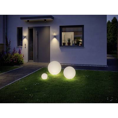 Ein moderner Hauseingang bei Nacht mit drei leuchtenden Kugeln im Garten. Licht strahlt von der Haustür und einem Fenster.