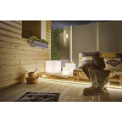 Gemütliche Terrasse bei Nacht, mit Holzpalettenmöbeln, kuscheligen Decken und indirekter Beleuchtung. Pflanzen im Hintergrund.