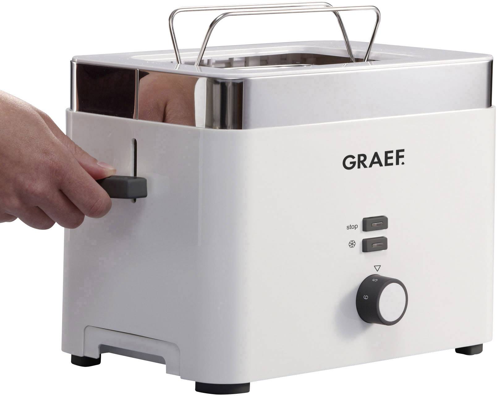 Eine Person betätigt den Hebel eines weißen Graef-Toasters mit zwei Schlitzen. Der Toaster hat Bedientasten und einen Drehknopf.