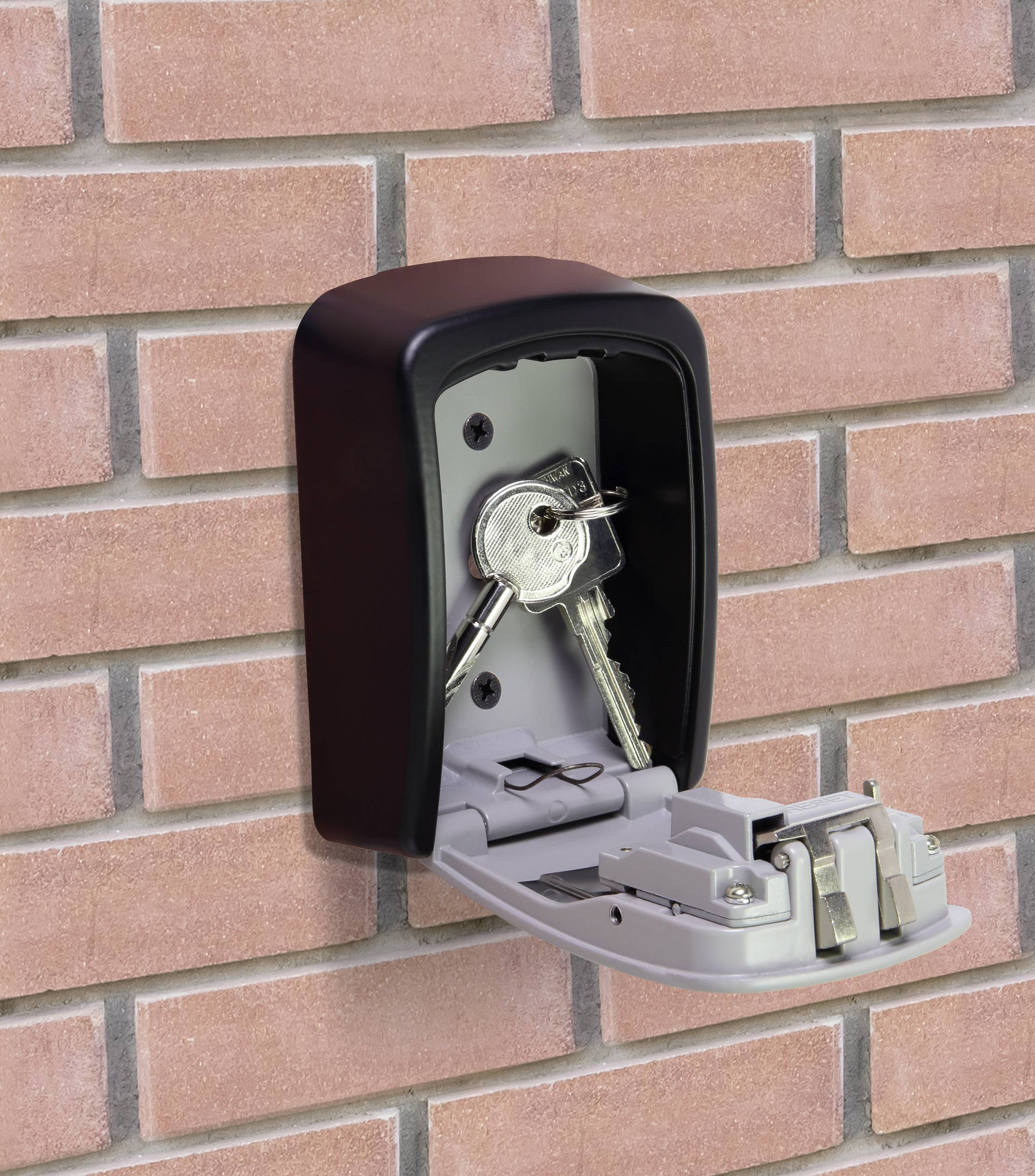 Ein Schlüsseltresor mit geöffnetem Deckel ist an einer Ziegelwand befestigt. Zwei Schlüssel sind im Inneren sichtbar.