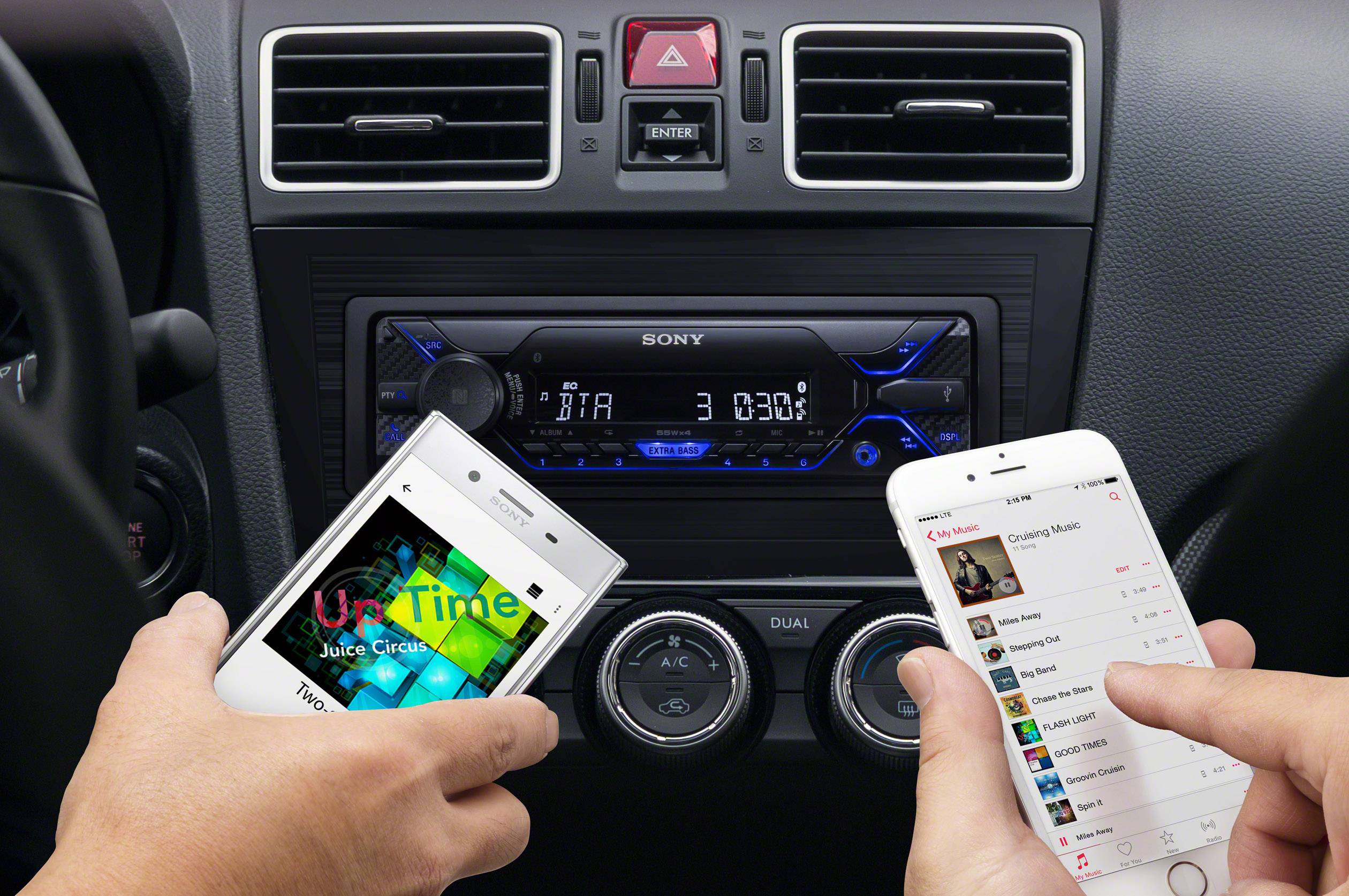Person koppelt Smartphone mit Autoradio über Bluetooth, um Musik abzuspielen. Hände halten ein weiteres Gerät, das Musik abspielt.
