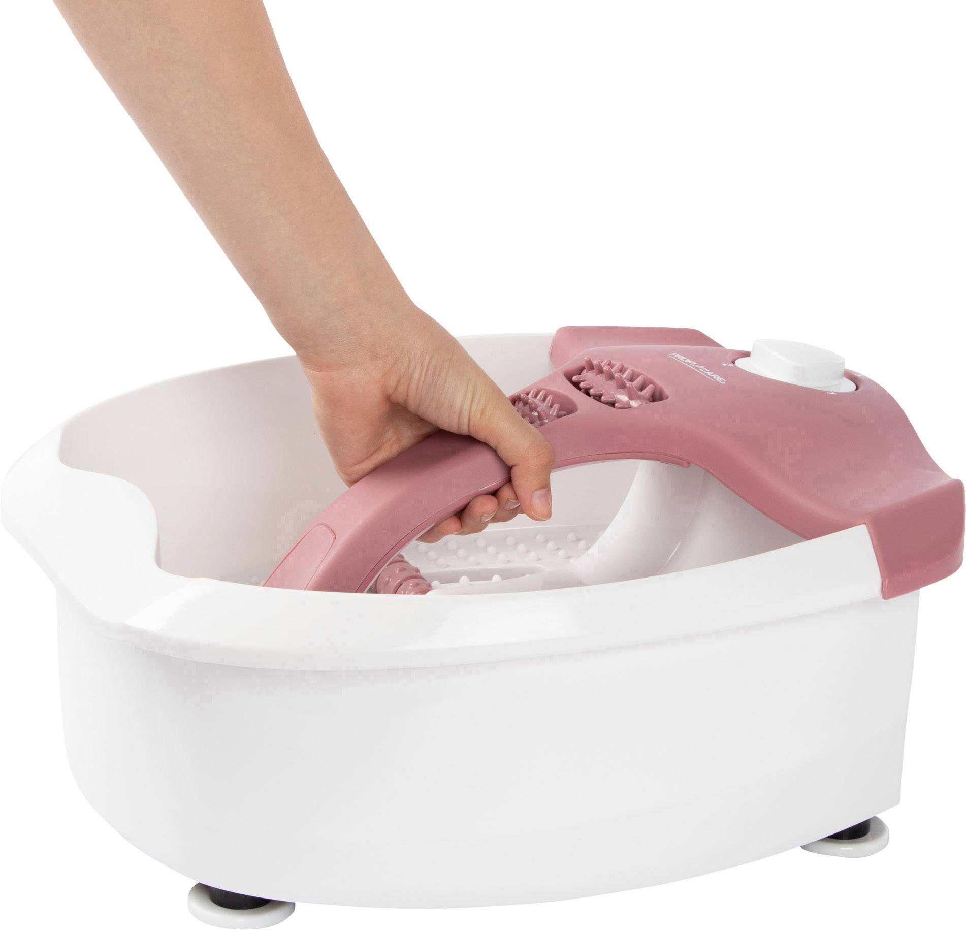 Eine Hand hält den Griff eines weißen und rosa Fußsprudelbads, das auf dem Boden steht.