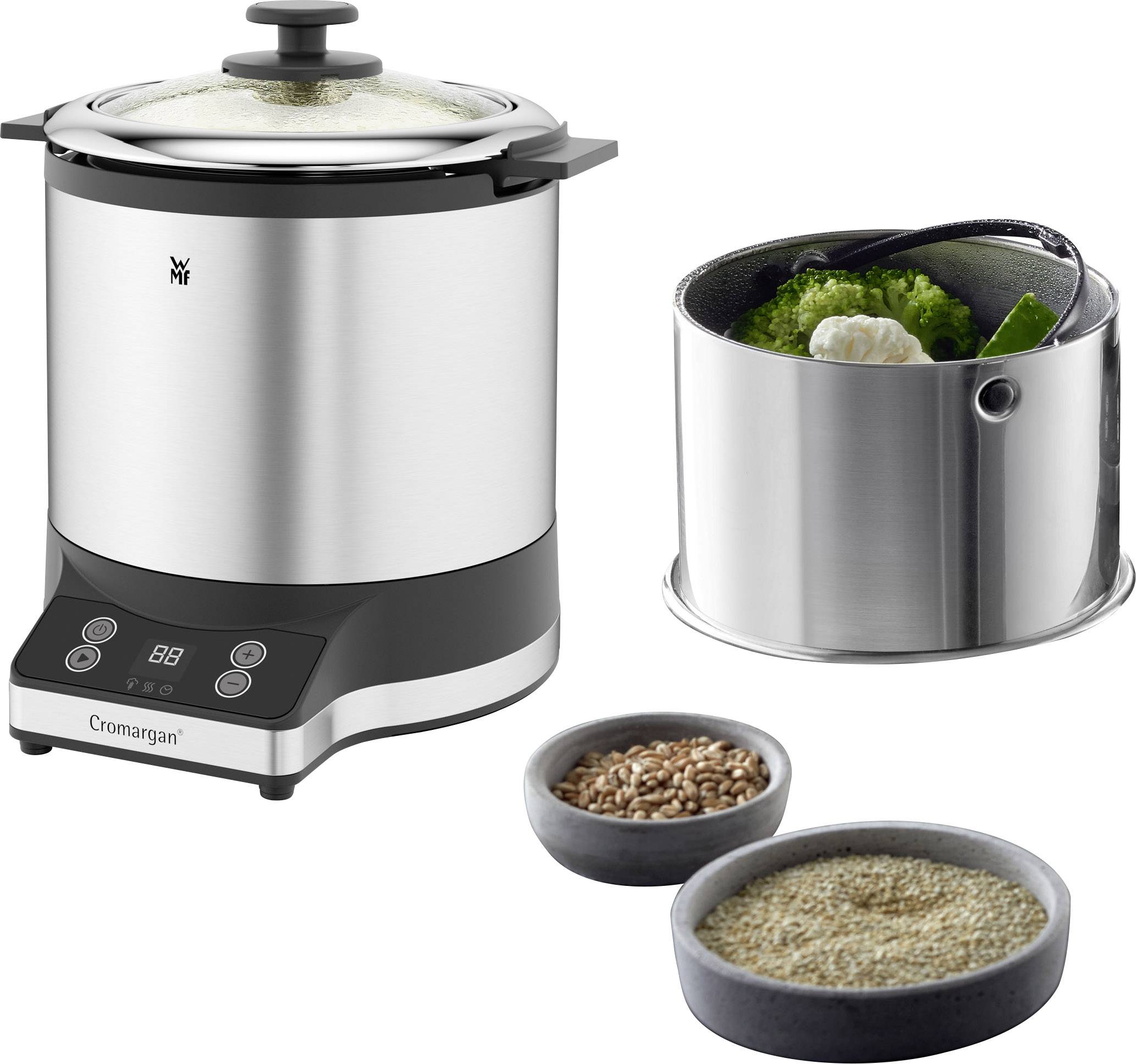 Ein elektrischer Dampfgarer mit einem geöffneten Einsatz, gefüllt mit Gemüse. Daneben stehen zwei Schalen mit Körnern.