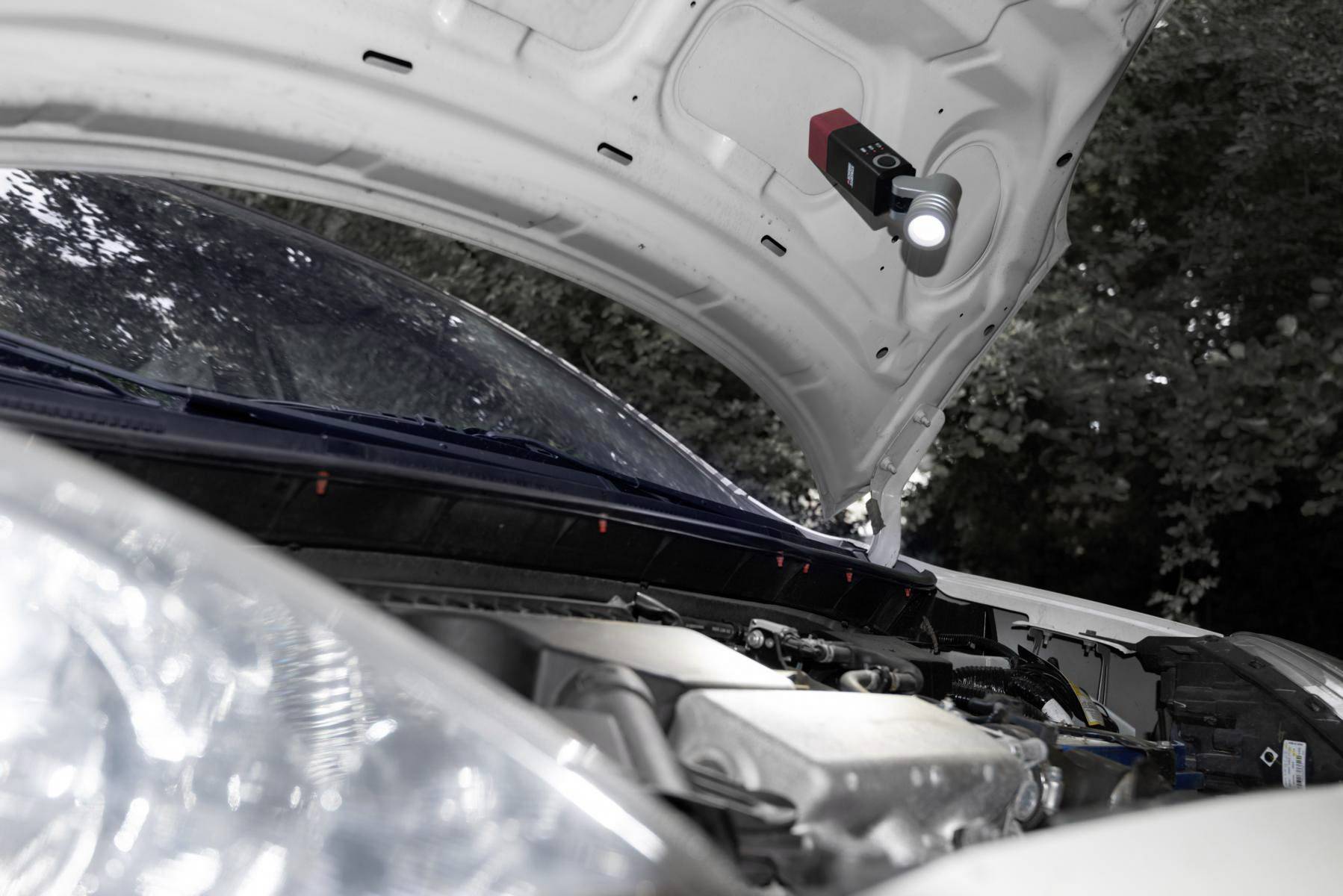 Motorhaube eines Autos ist geöffnet, ein Inspektionswerkzeug mit Licht ist an der Motorhaube montiert. Der Motorraum ist sichtbar.