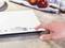 Person legt Finger auf digitale Küchenwaage auf einem Küchenarbeitsplatz mit verstreutem Zucker und roten Äpfeln im Hintergrund.