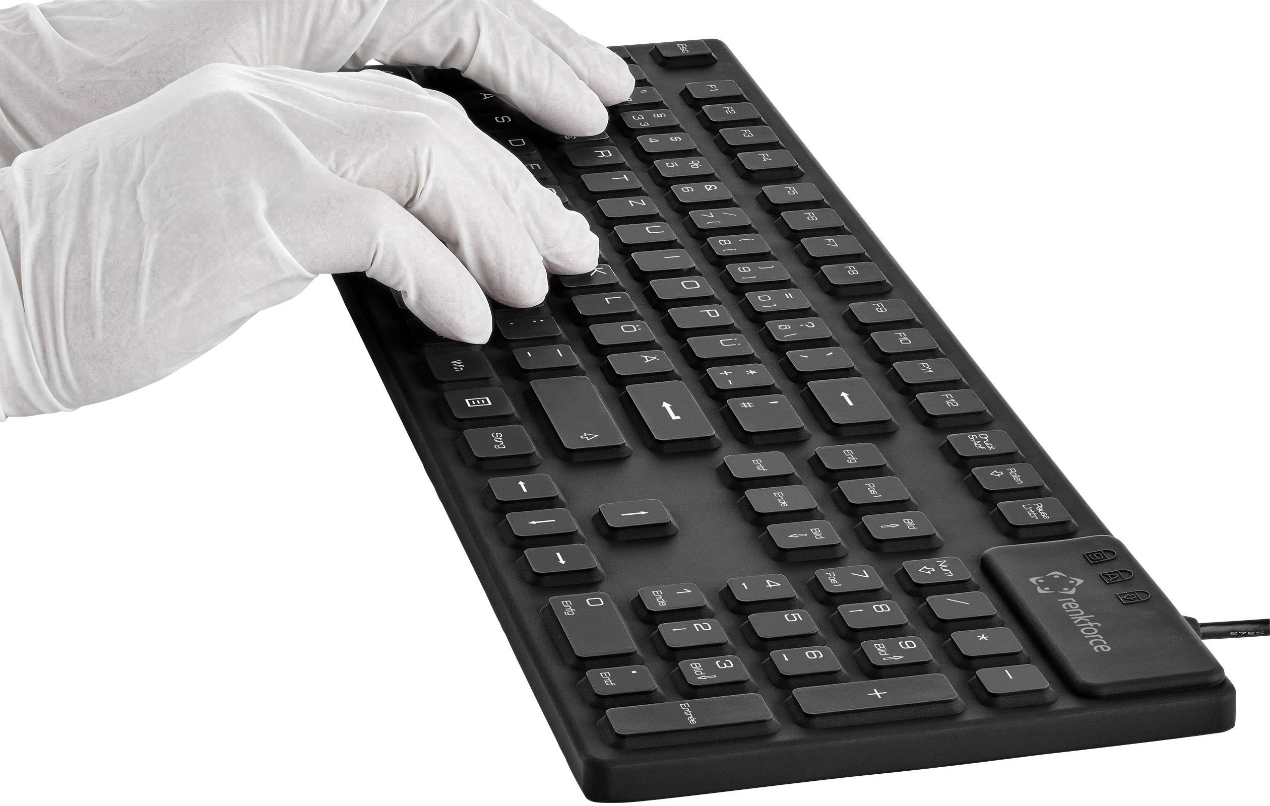 Eine schwarze Tastatur wird von einer Person mit weißen Handschuhen benutzt.