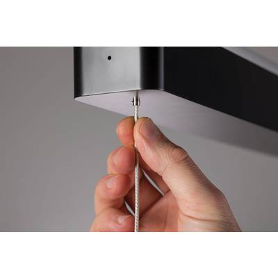 Eine Hand zieht an einem Seil, das an einem schwarzen rechteckigen Objekt befestigt ist, möglicherweise eine Lampe oder Vorrichtung.