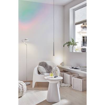 Helles Wohnzimmer mit einem weißen Sessel, auf dem ein Fellkissen liegt. Ein kleiner Tisch mit Getränk und Smartphone steht daneben.