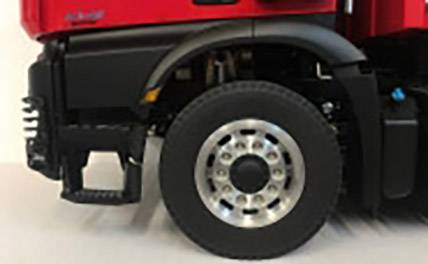 Ein roter Lkw von der Seite, fokussiert auf das Vorderrad und den Kotflügel. Teil der Karosserie und schwarze Details sind sichtbar.