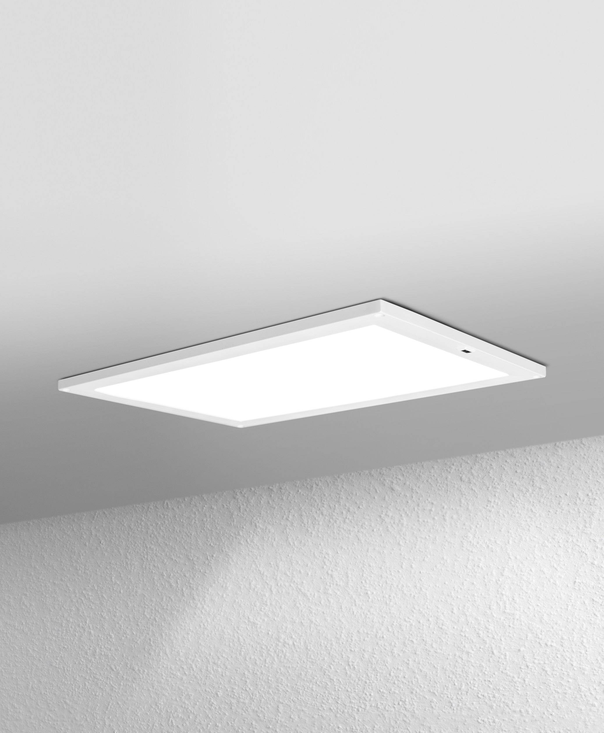 Eine rechteckige Deckenlampe strahlt helles, diffuses Licht aus. Sie ist schlicht und modern gestaltet, an einer weißen Decke befestigt.