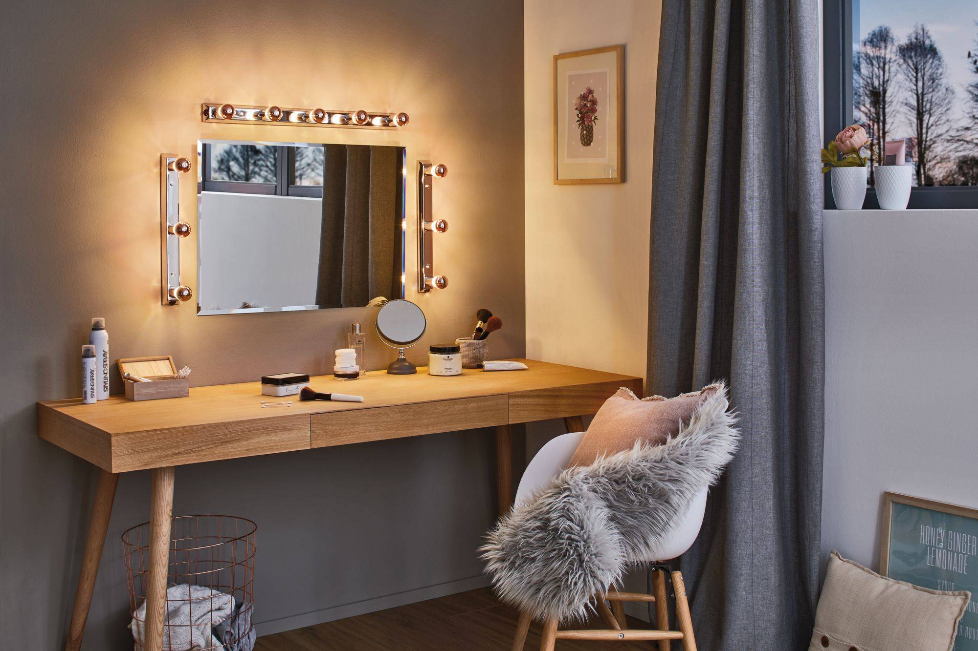 Ein stilvoller Schminktisch mit beleuchtetem Spiegel, Kosmetikartikeln und Dekoration. Ein Fenster bietet Tageslicht für die Ecke.