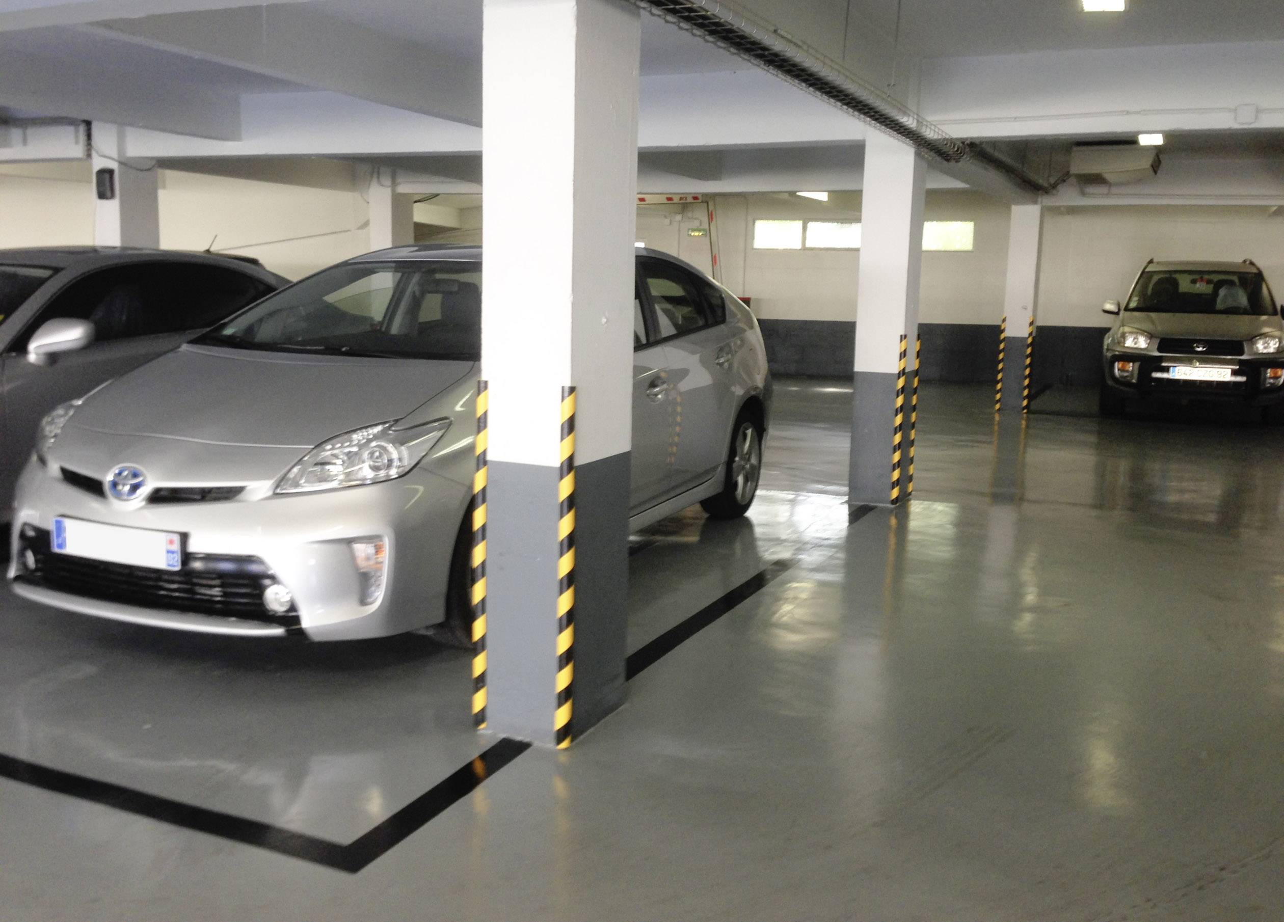 Ein Tiefgaragenparkplatz mit zwei geparkten Autos, eines davon ist ein silbernes Fahrzeug in der Mitte.