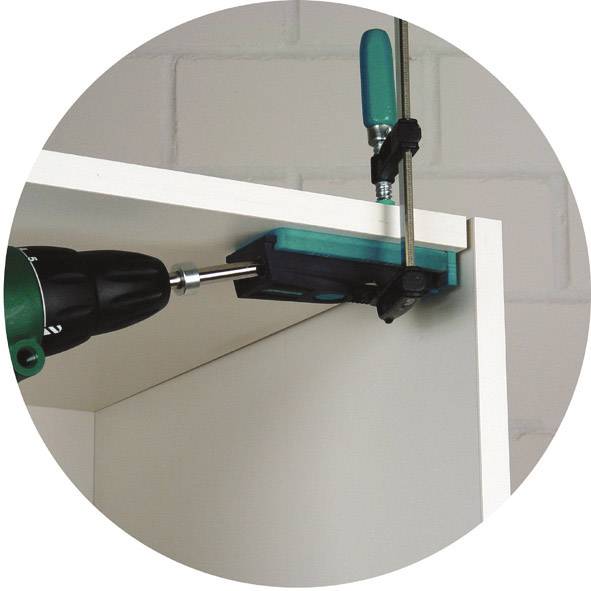 Ein Regal wird mit einem Metallwinkel und einer Schraube aneinander befestigt. Eine Bohrmaschine wird benutzt, um die Schraube einzudrehen.