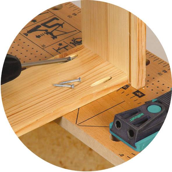 Holzverbindung mit zwei Schrauben und passenden Bohrlöchern. Ein Winkelmesswerkzeug liegt auf einem Holzbalken.