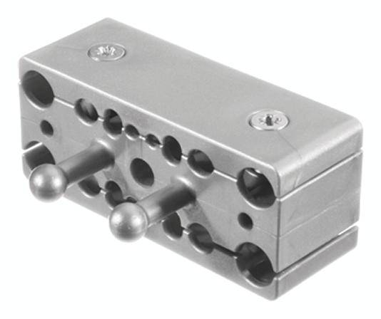 Rechteckiger Metallblock mit mehreren Löchern und zwei hervorstehenden Bolzen, vermutlich Teil einer mechanischen Vorrichtung.