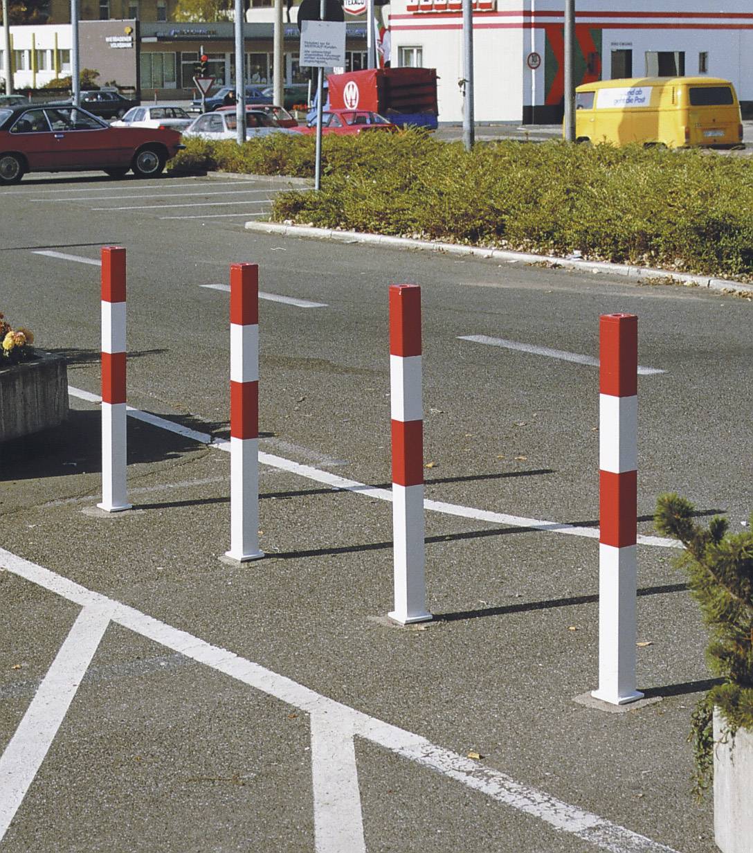 'Vier rot-weiße Poller auf einem Parkplatz, die den Zugang für Autos blockieren.'