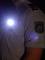 Person in Polizei-Uniform mit Schulterabzeichen. Eine Taschenlampe leuchtet an der Brust des Hemds. Beleuchtung und Uniform sind im Fokus.