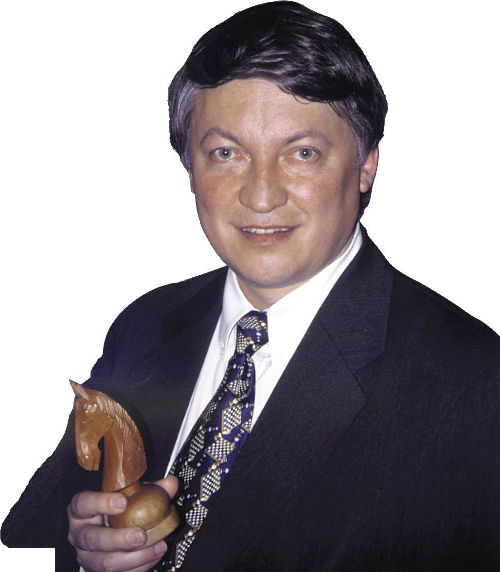 Eine Person in formeller Kleidung hält eine Schachfigur (Springer) aus Holz.