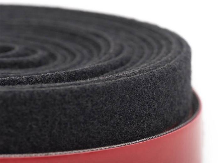 Eine eng aufgerollte schwarze Schaumstoffmatte liegt auf einem roten Untergrund.