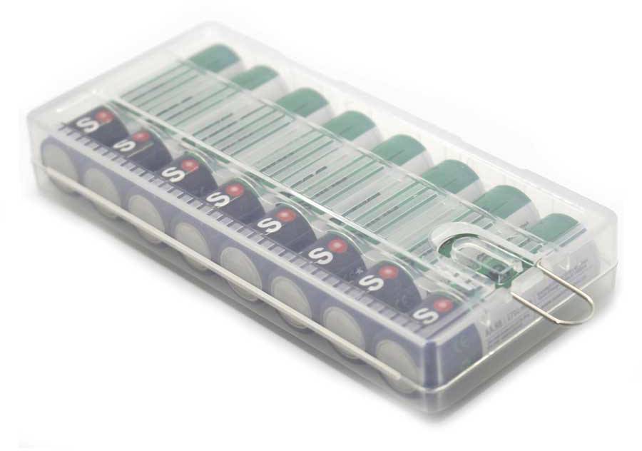 Eine transparente Box mit grün-weißen Batterien, die nebeneinander angeordnet sind. Ein Metallclip hält die Box verschlossen.