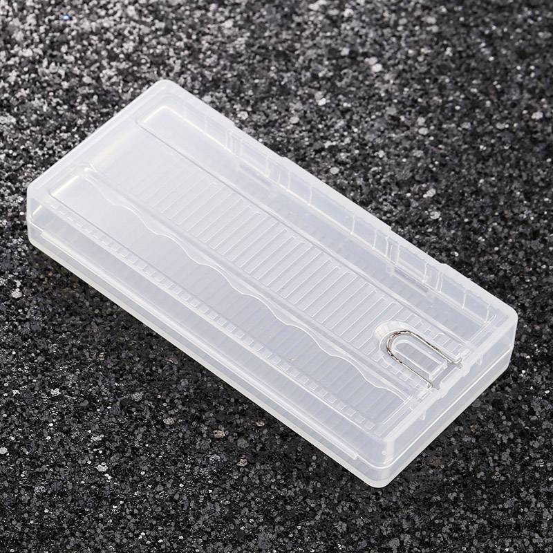 Durchsichtige rechteckige Plastikbox mit Schiebedeckel und U-förmigem Hängeloch, liegt auf dunkler, rauer Oberfläche.