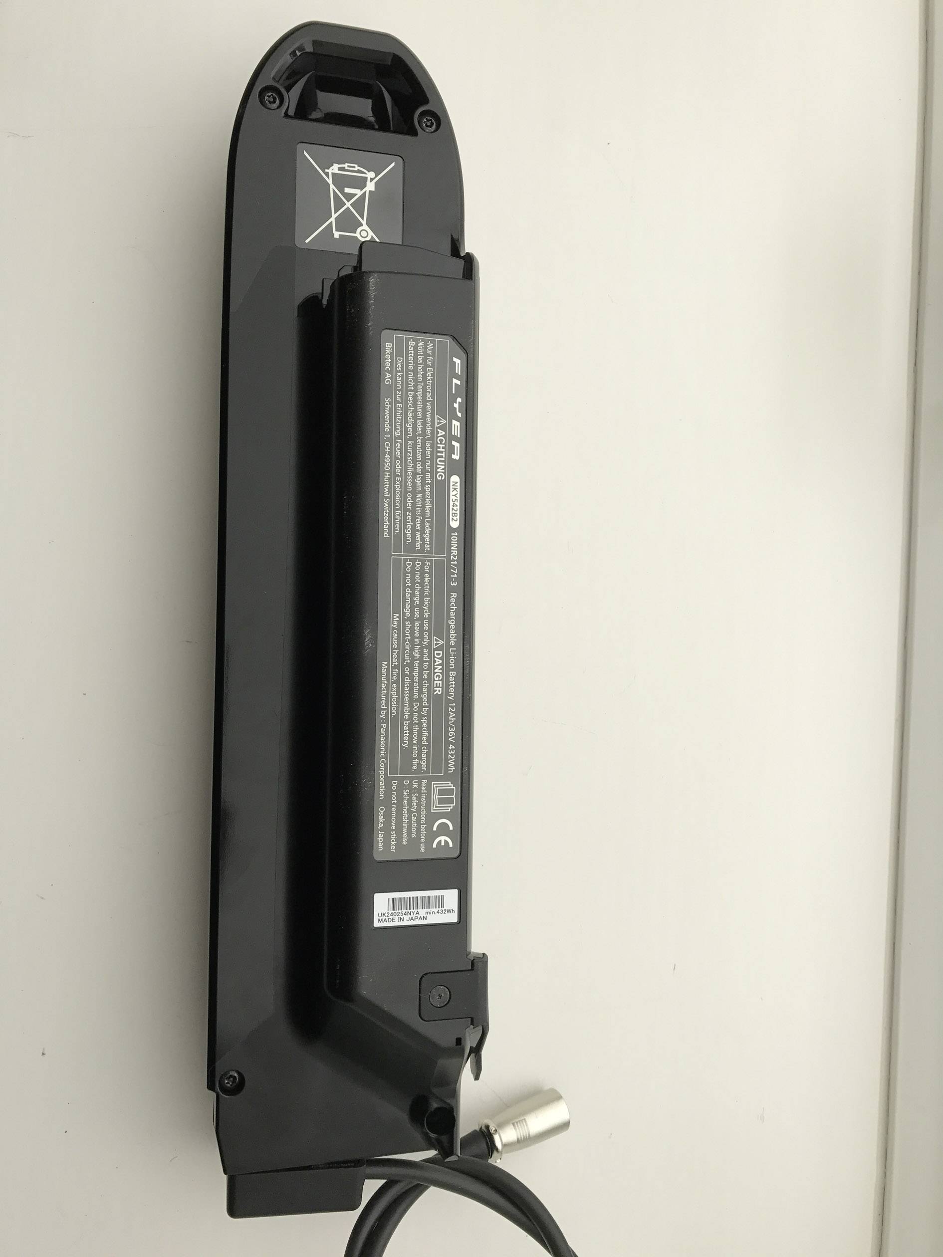 Ein elektrisches Fahrrad-Akkupack mit schwarzem Gehäuse, darauf Sicherheits- und Herstellerinformationen auf einem Etikett.