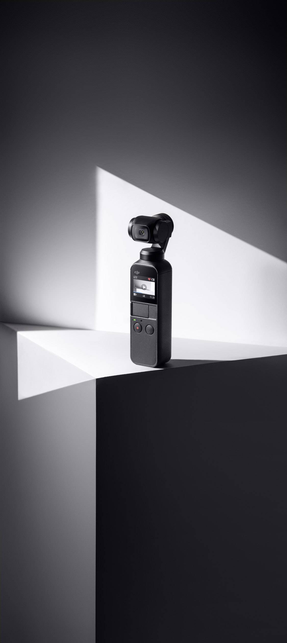 Eine kompakte Handkamera mit Gimbal steht stabil auf einer künstlerisch beleuchteten geometrischen Form, die moderne Architektur erinnert.